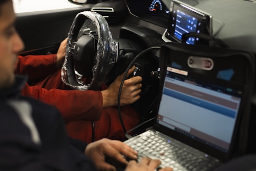A man sitting in a car using a laptop computer