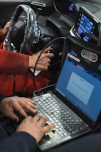 A man sitting in a car using a laptop computer