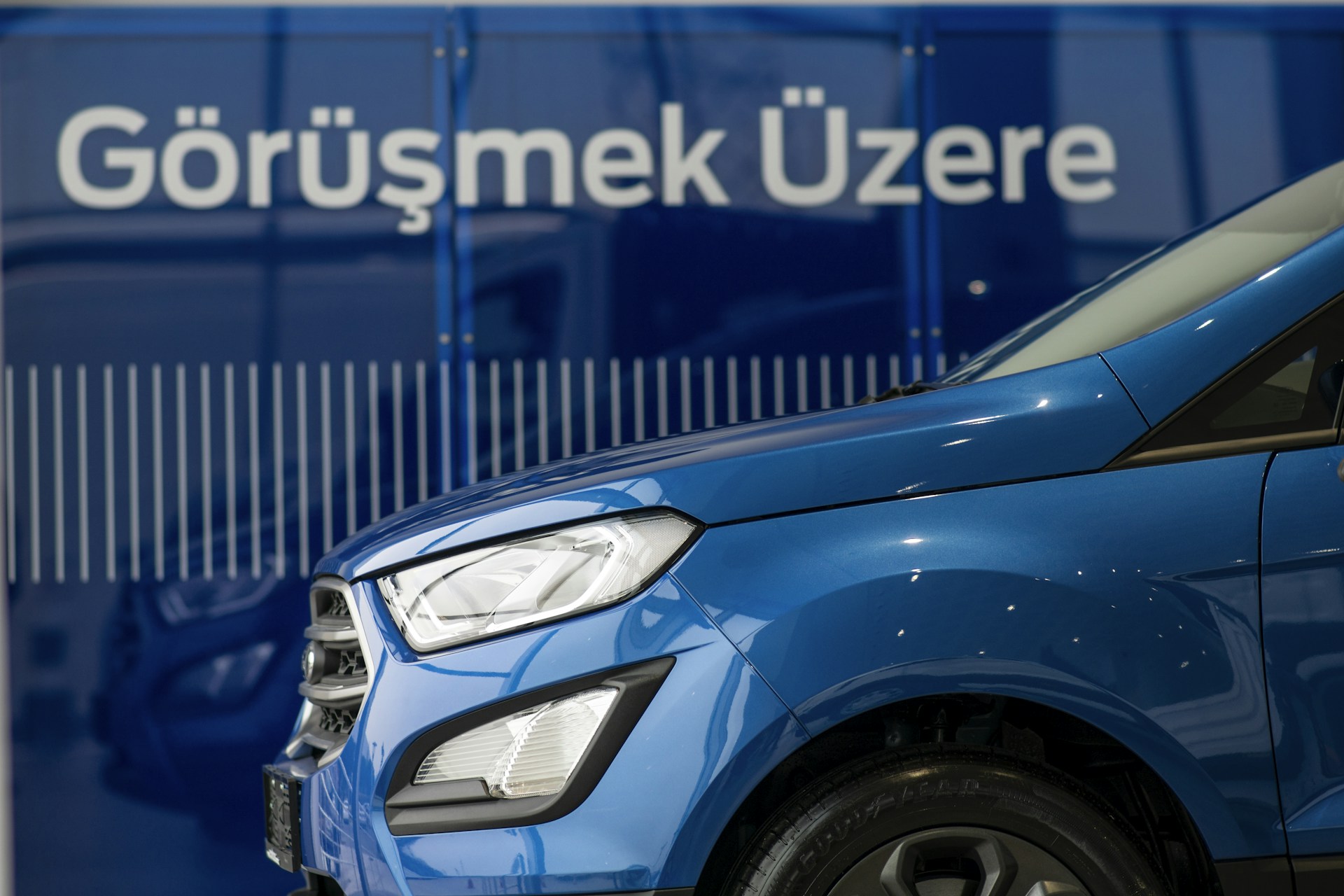 A blue car parked in front of a sign