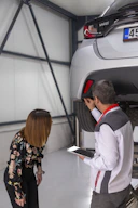 A man and a woman looking under a car