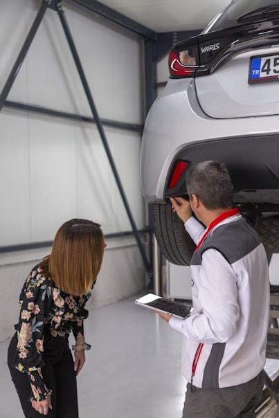 A man and a woman looking under a car