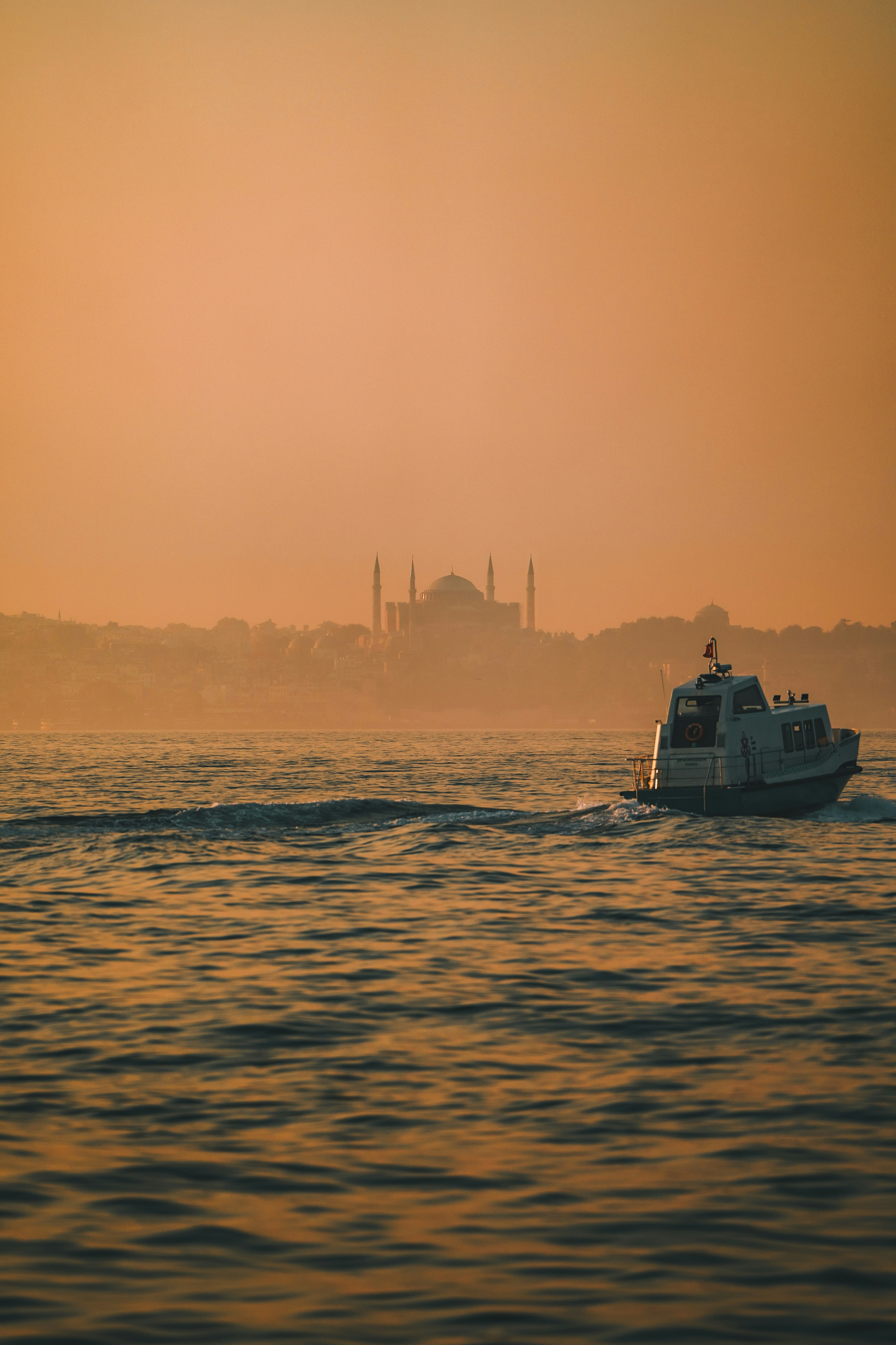 A boat in a body of water with a city in the background