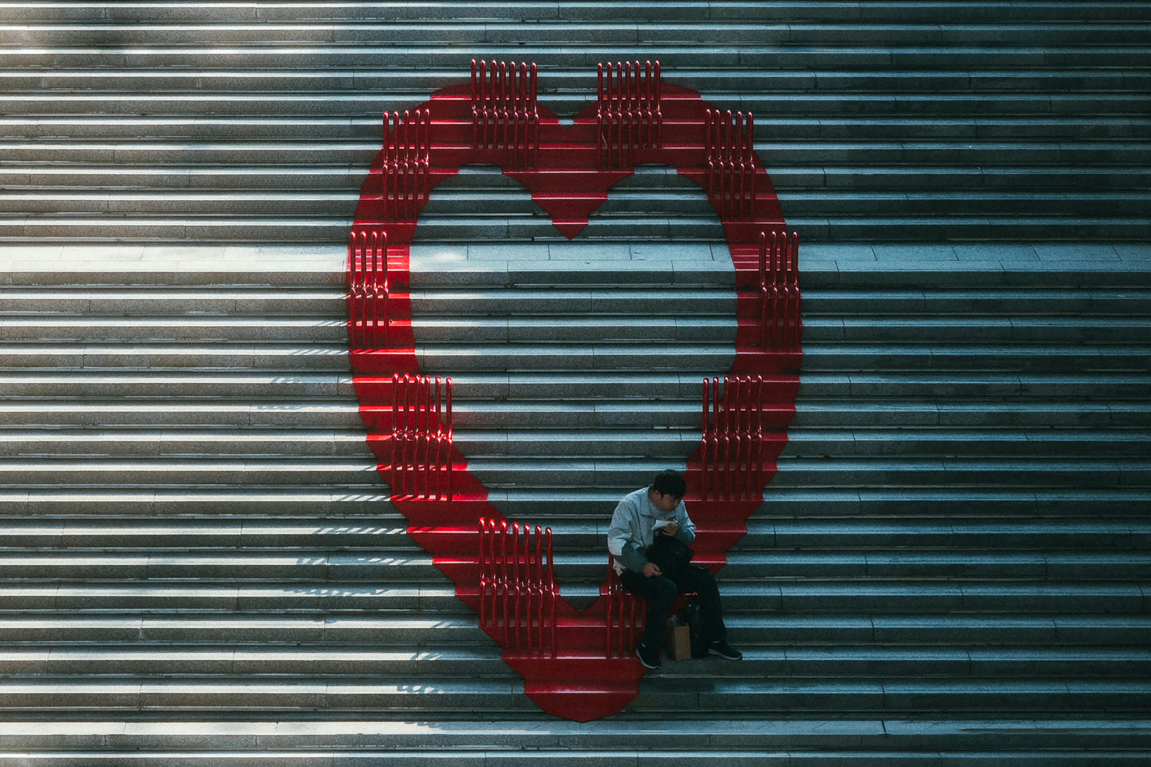 A man sitting on a bench in front of a giant heart