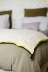 A bed with a yellow pillow on top of it