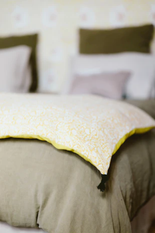 A bed with a yellow pillow on top of it