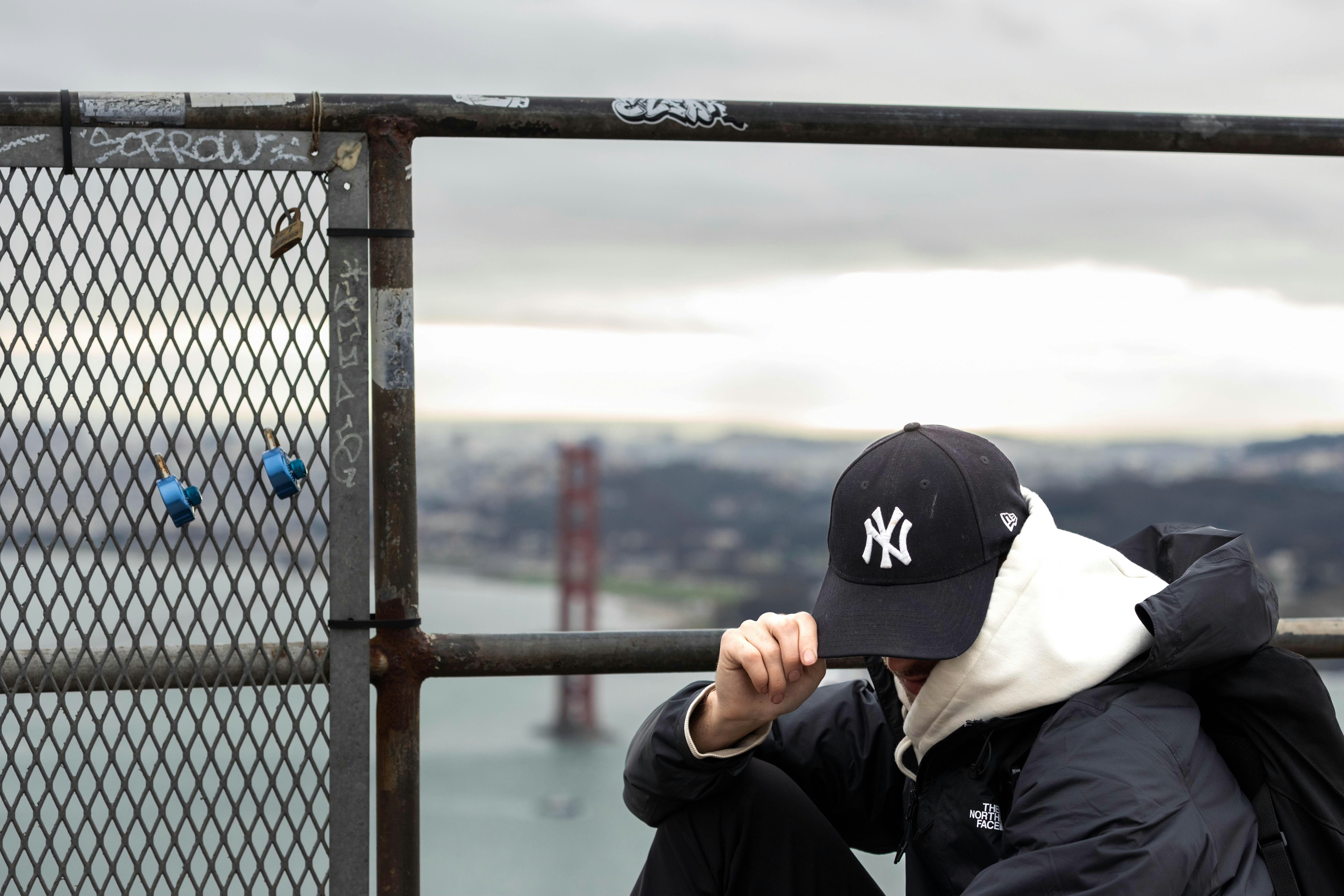 A man sitting on a fence looking at the water
