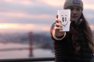 A woman holding a cup with a smiley face drawn on it