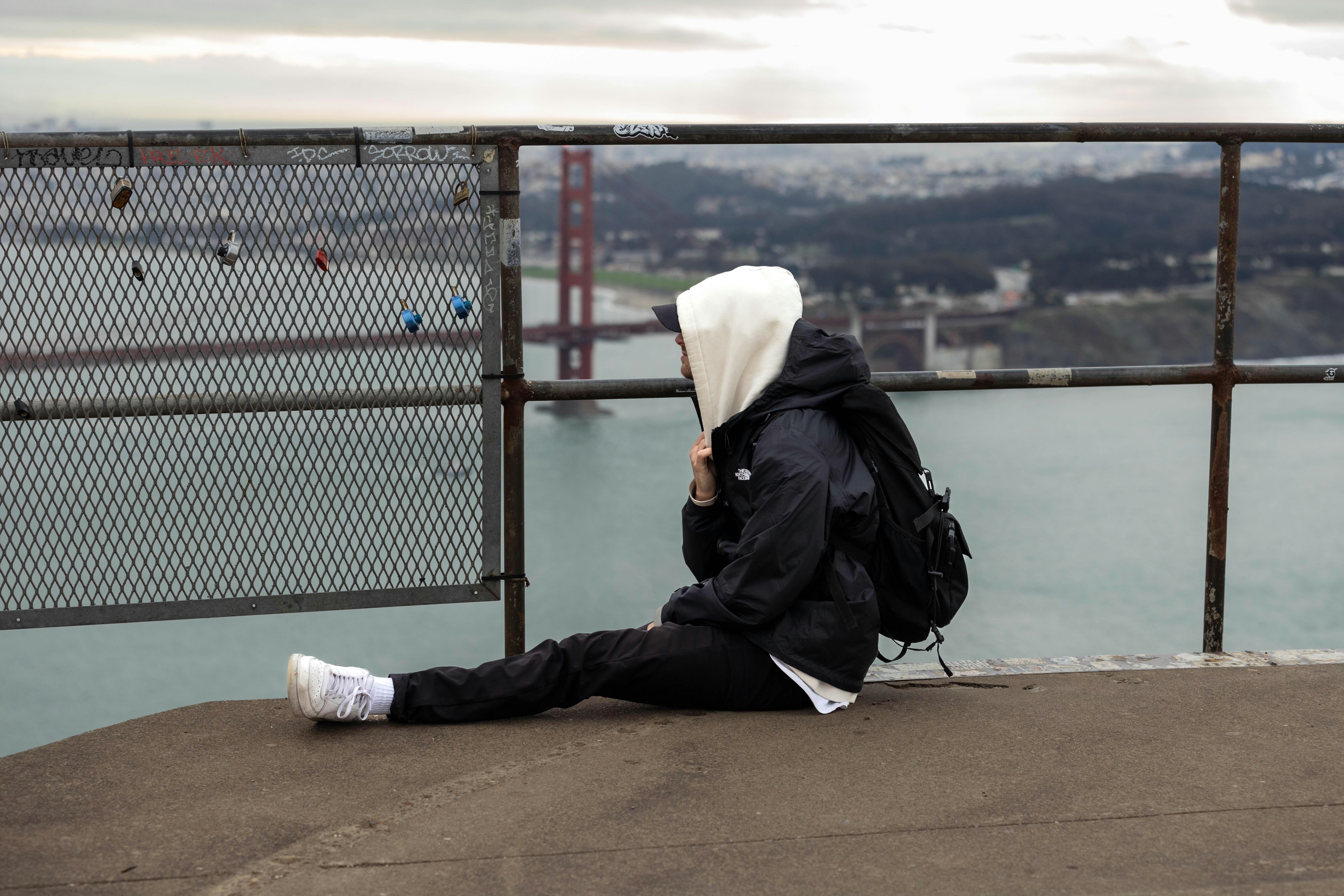 A person sitting on a ledge looking at the water