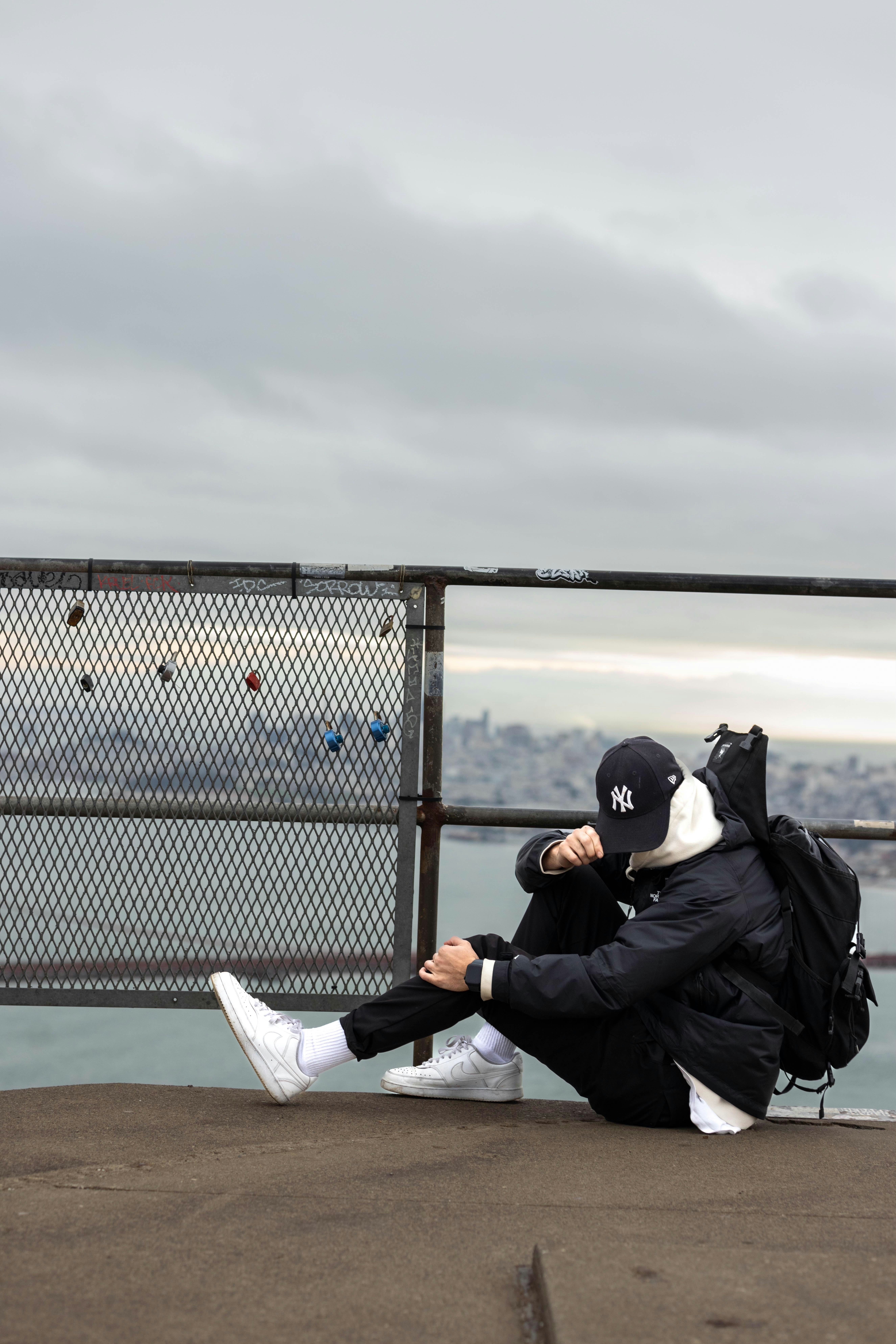 A person sitting on a ledge with a backpack