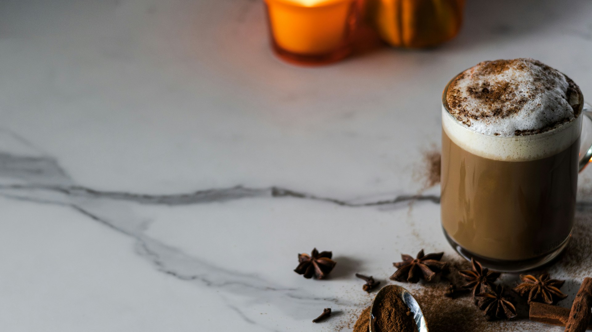A cup of hot chocolate and cinnamon on a marble table