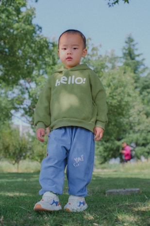 A young boy in a green sweatshirt and blue pants