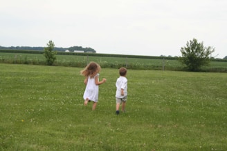Two young children playing in a field of grass