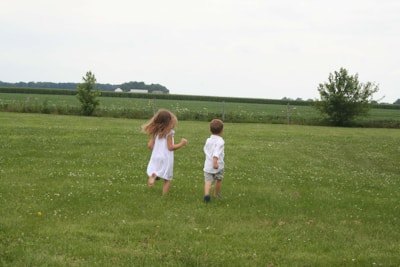 Two young children playing in a field of grass