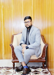 A man in a suit and tie sitting on a chair