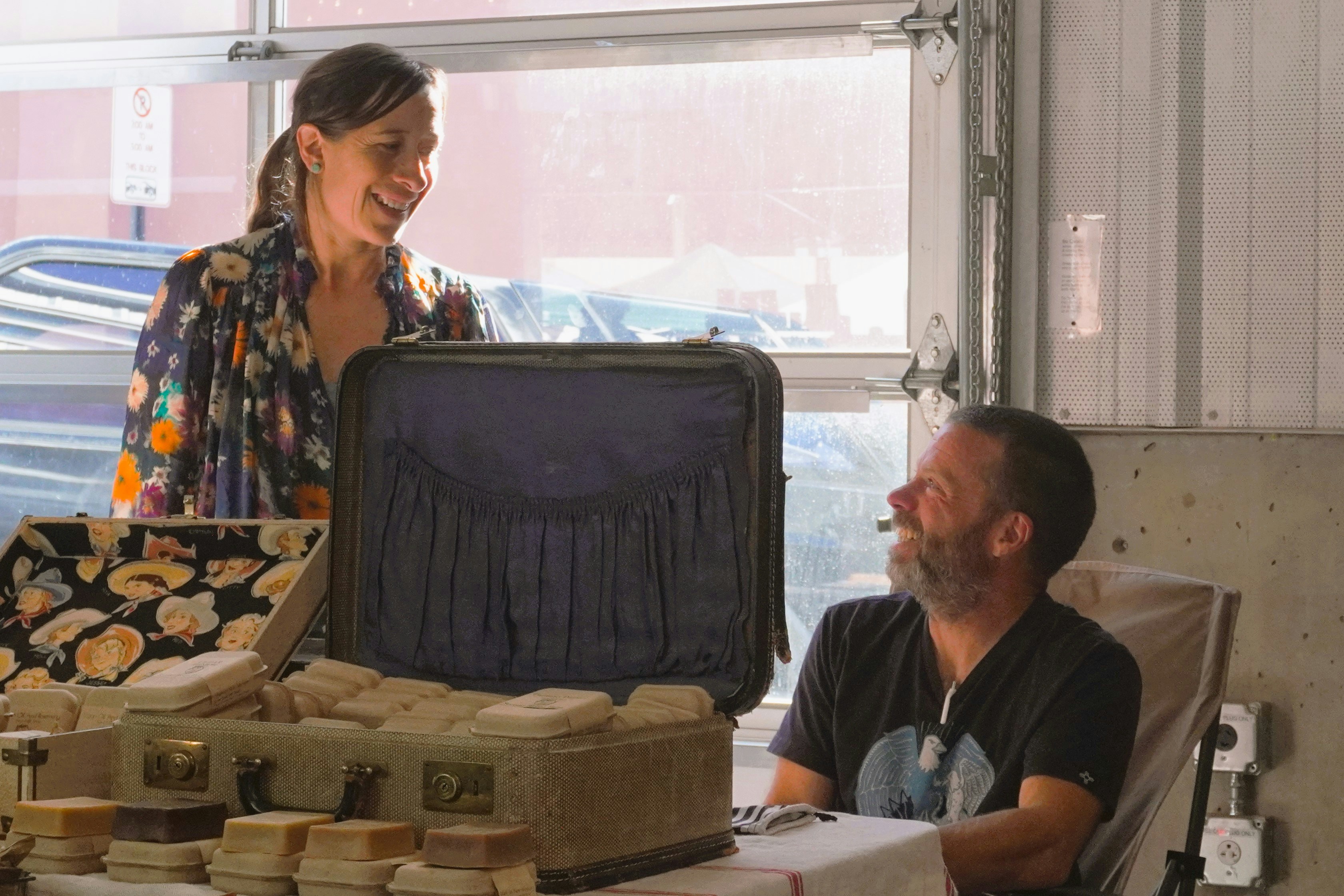 Una mujer de pie junto a un hombre con una maleta