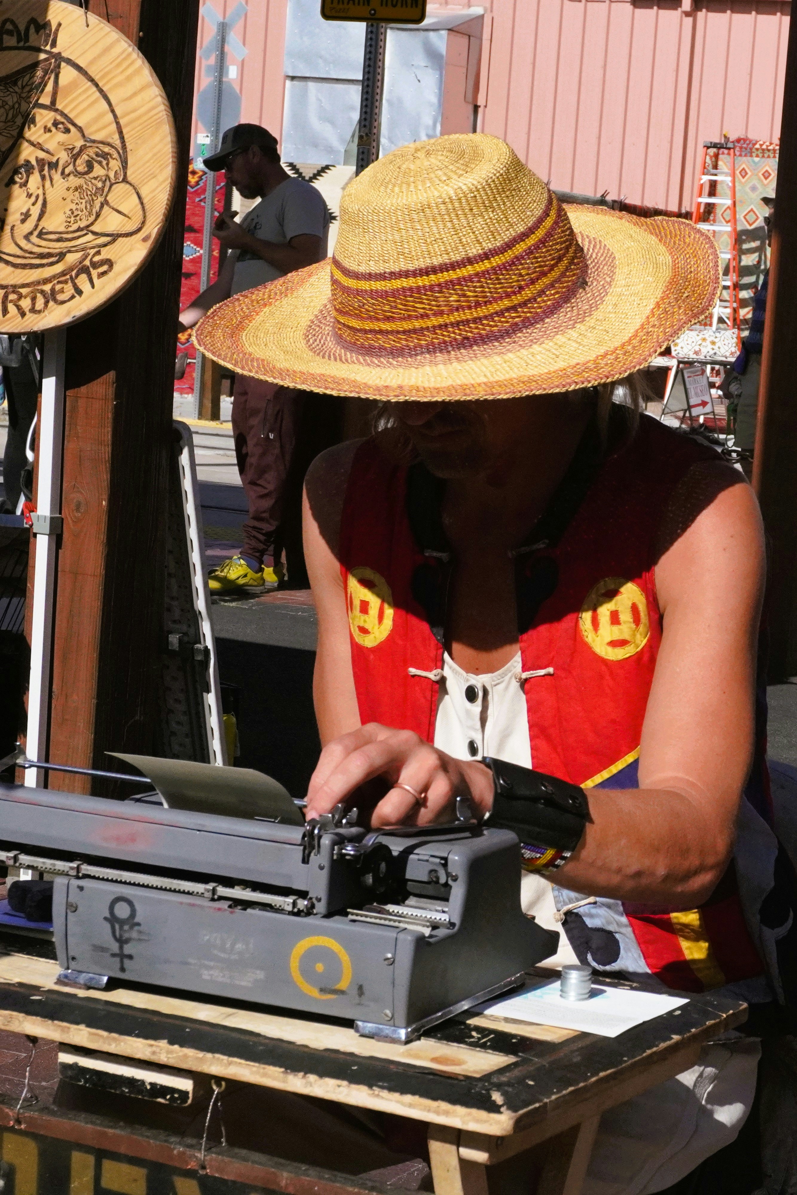 Una mujer con sombrero de paja escribe en una máquina de escribir