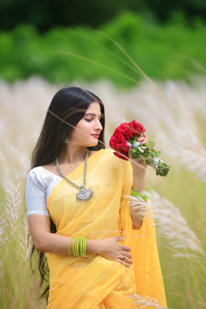 A woman in a yellow handloom saree holding flowers