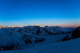 A view of a snowy mountain range at dusk