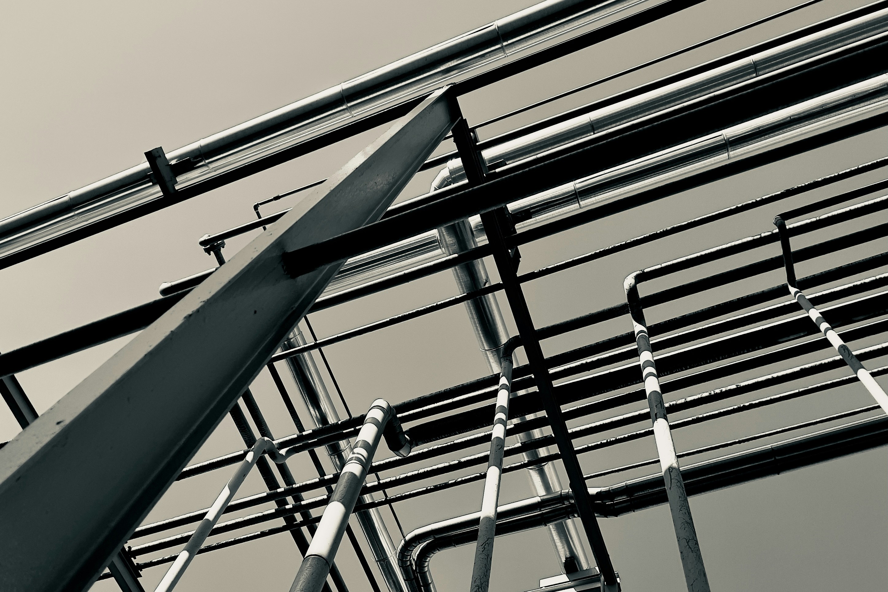 Industrial steel pipes arranged in parallel rows, grey metallic factory floor, dark background