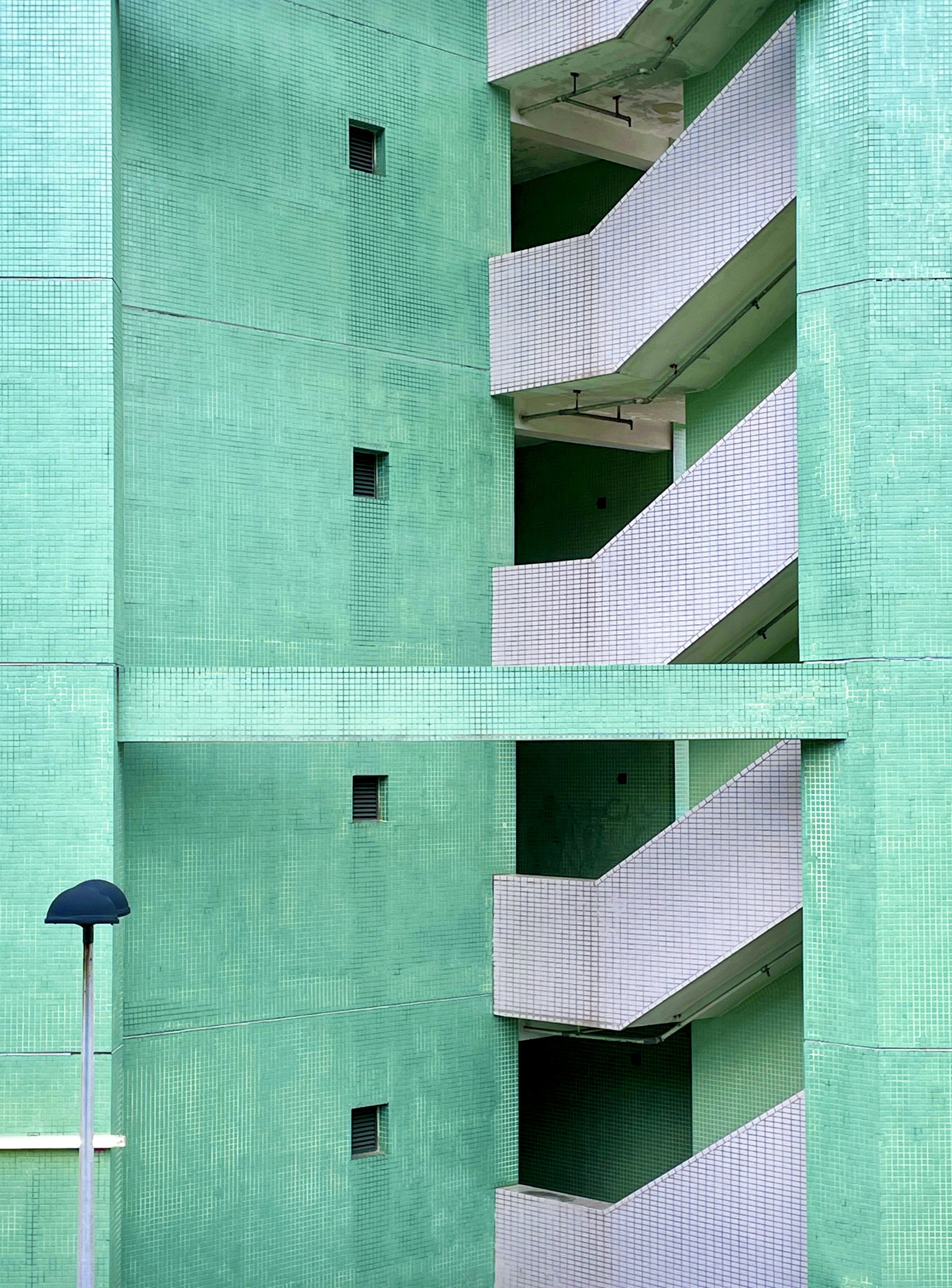 A green building with balconies and a street light