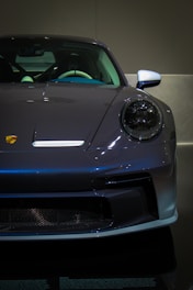A grey sports car is on display in a dark room