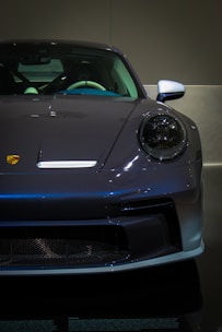 A grey sports car is on display in a dark room