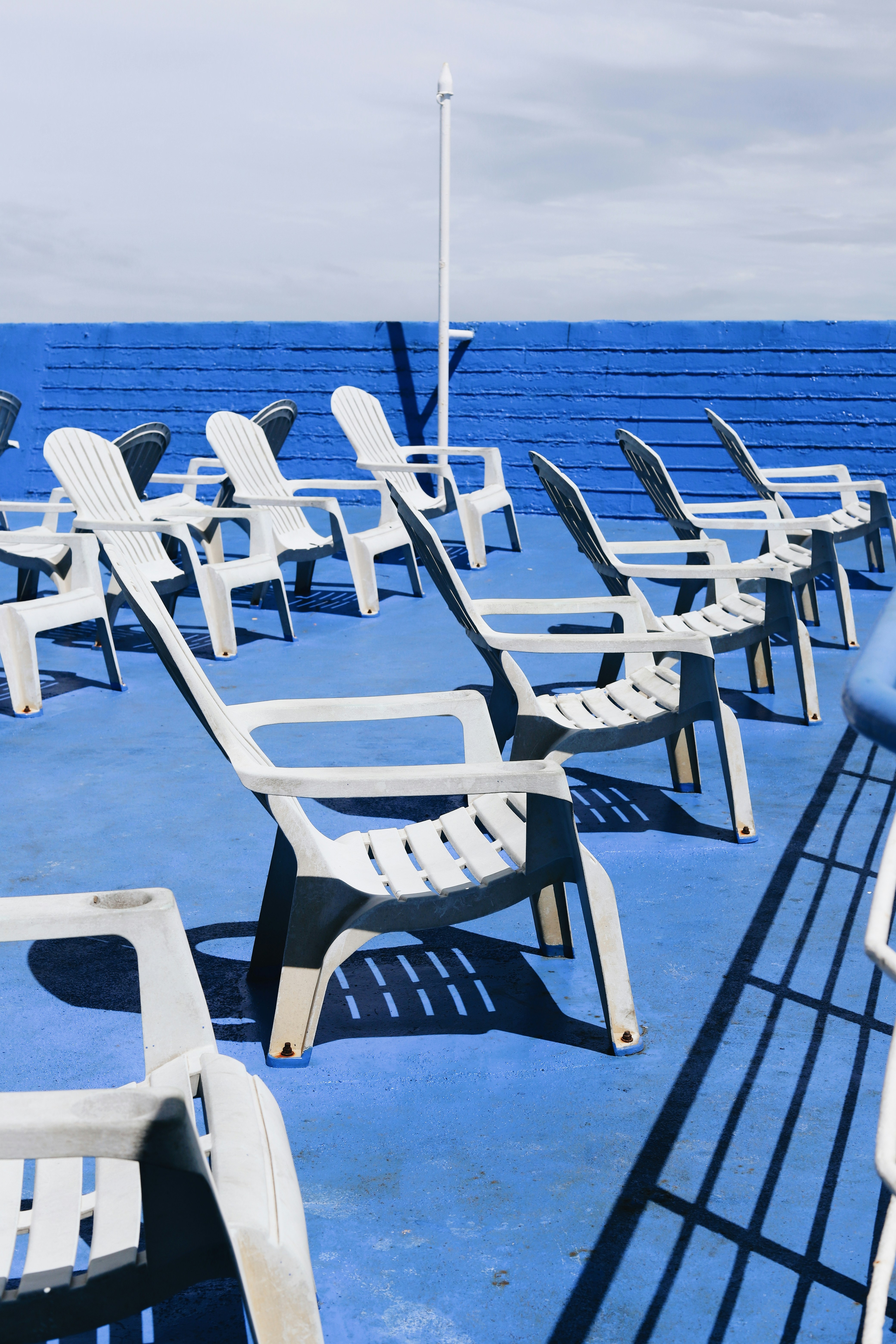 Uma fileira de cadeiras brancas sentadas em cima de um piso azul