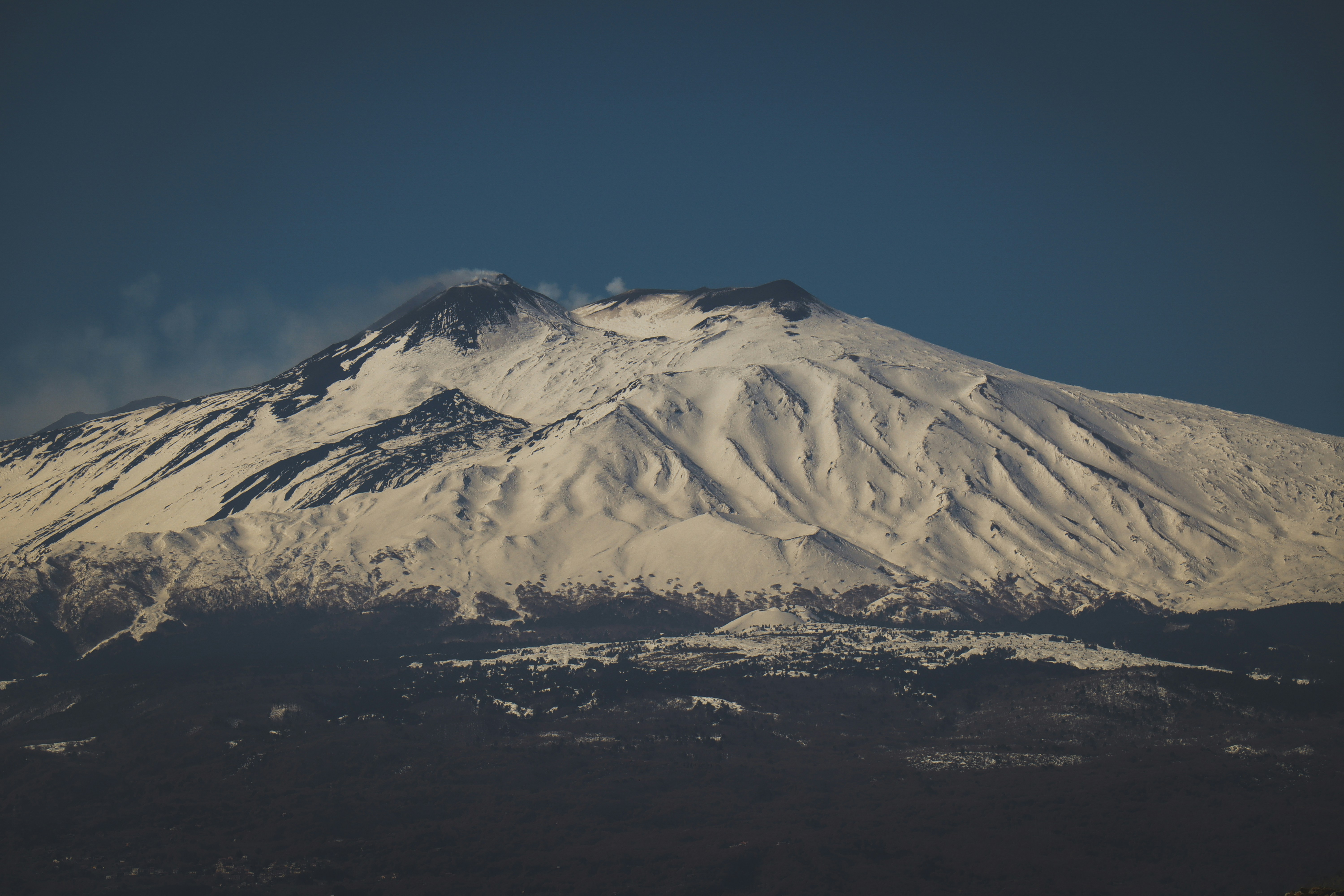 A large mountain covered in snow under a blue sky