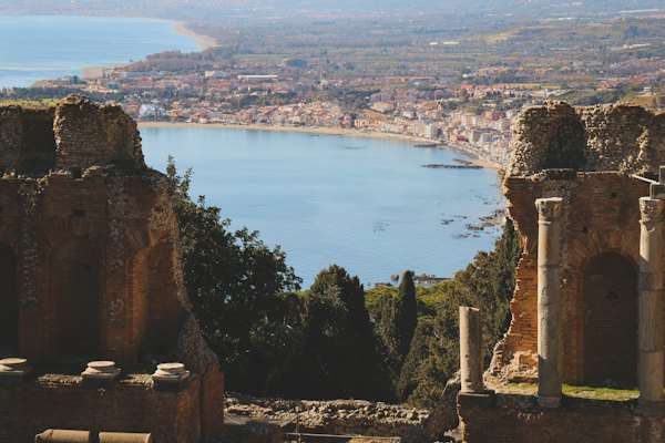 A large body of water sitting next to a lush green hillside — Taormina, Italy