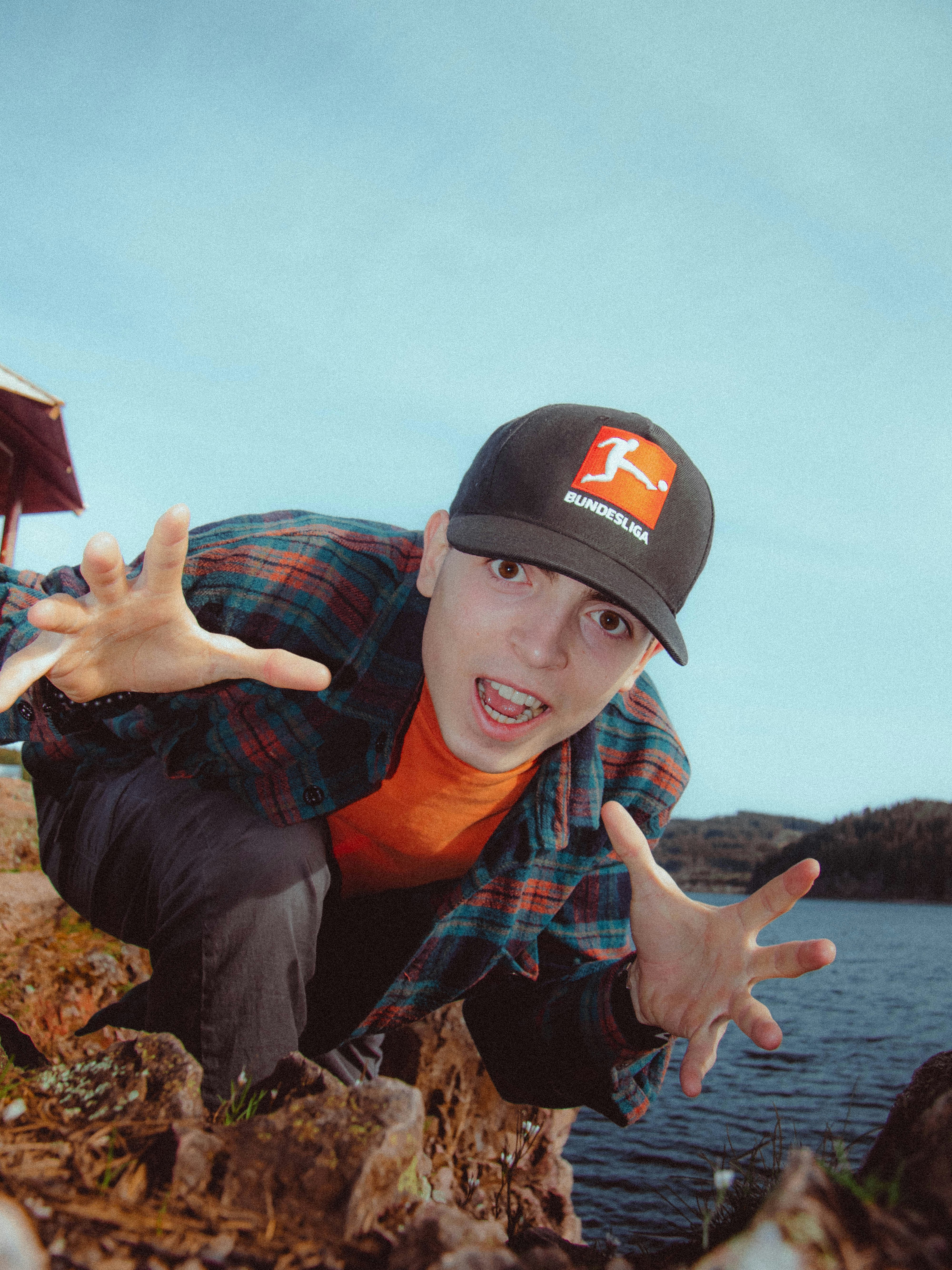 Un jeune homme posant pour une photo devant un plan d’eau