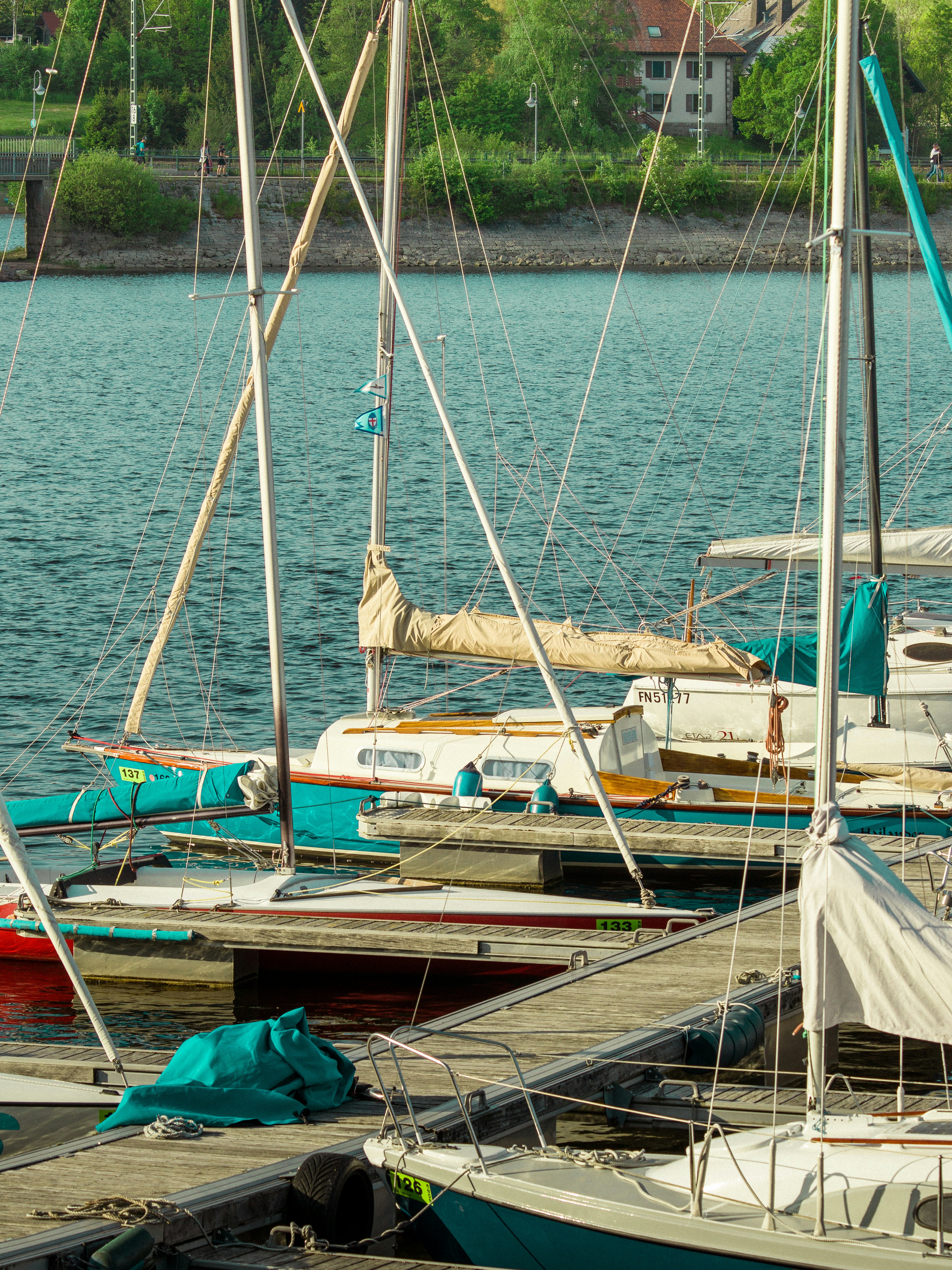 Sun-drenched coastal dock with polished brass fittings, navy rope coils, emerald green water, bright open sky and sailboat