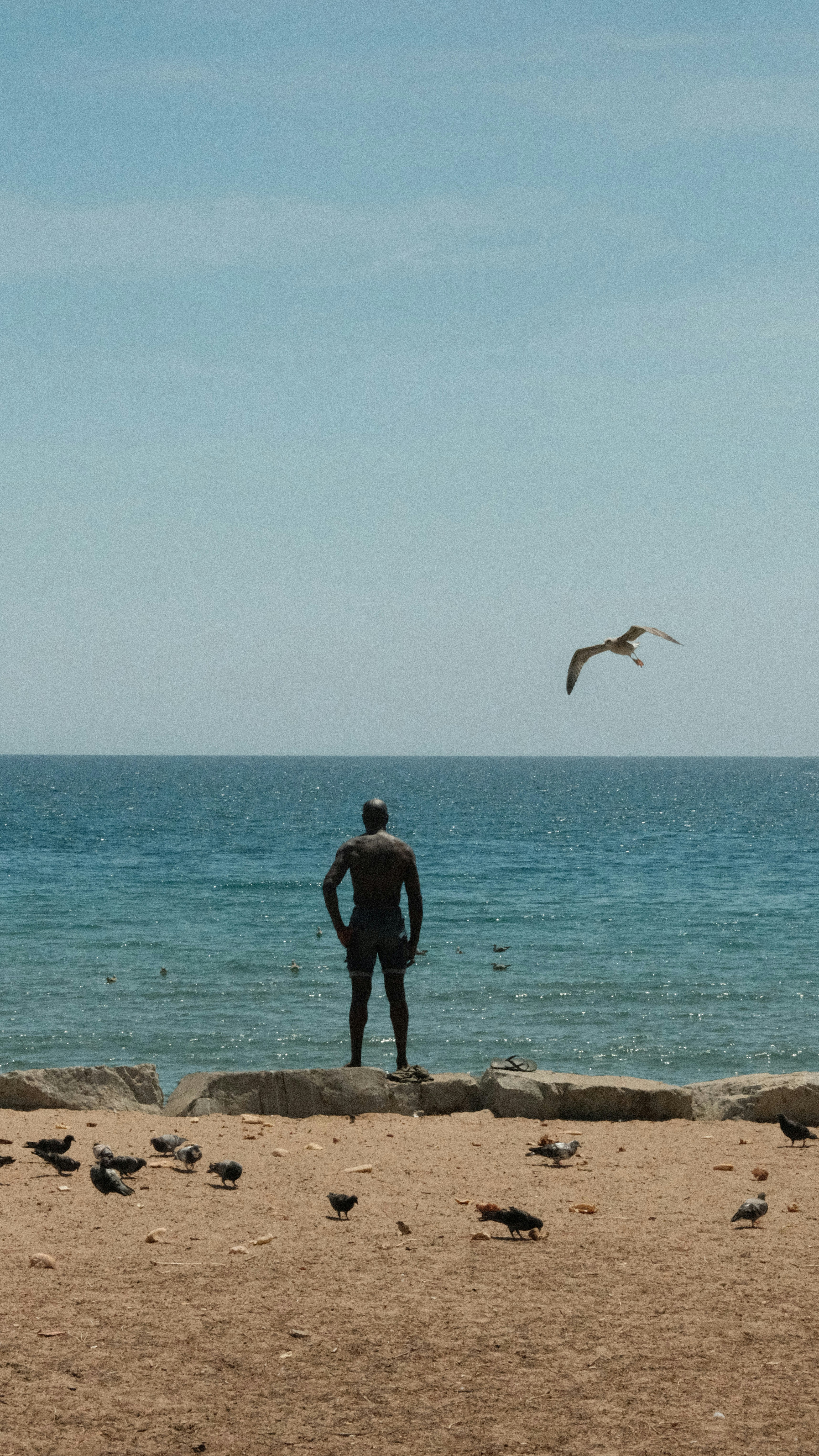 A man standing on a beach next to the ocean photo – Free Beach Image on ...