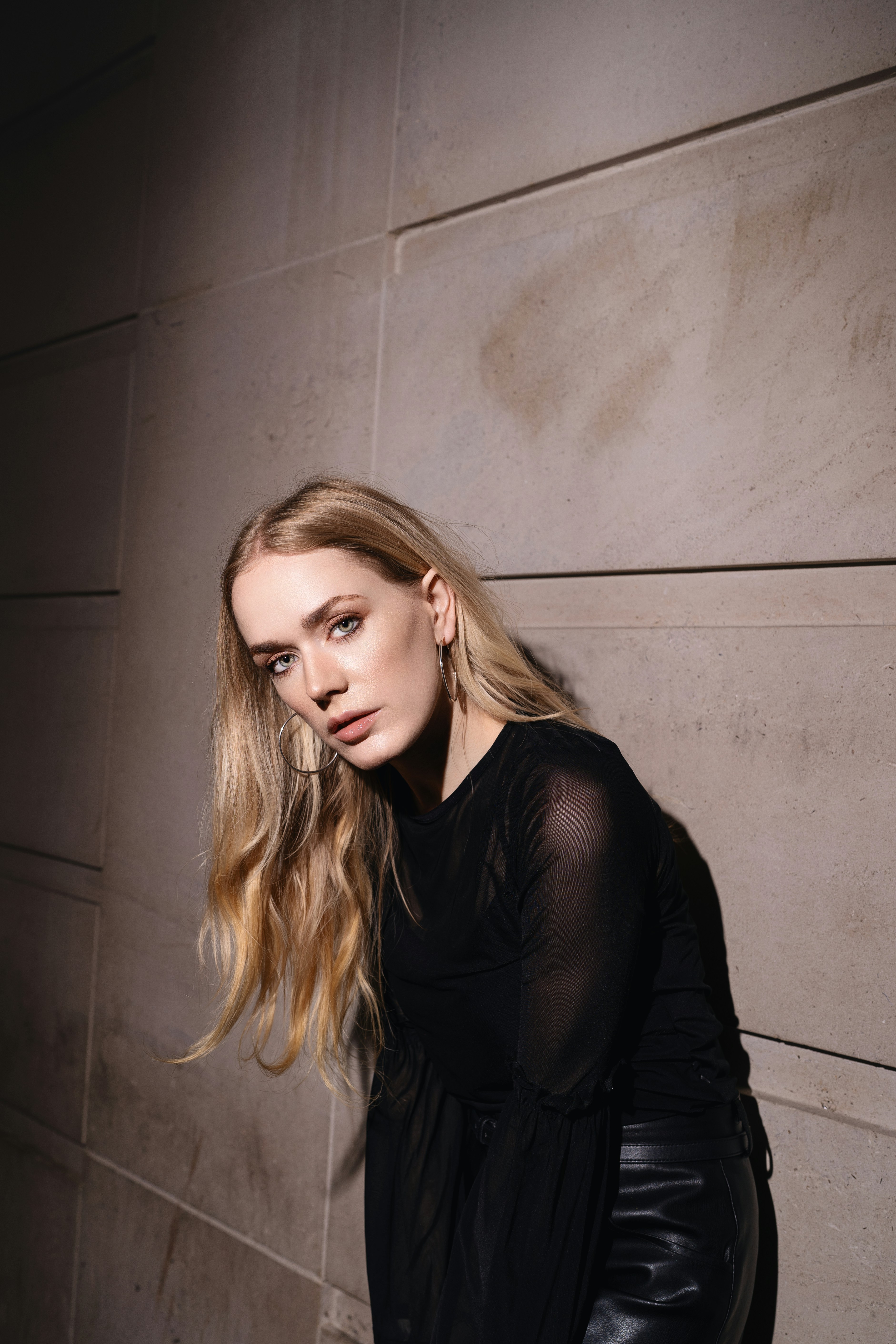 A woman leaning against a wall with her hand on her hip photo – Free ...