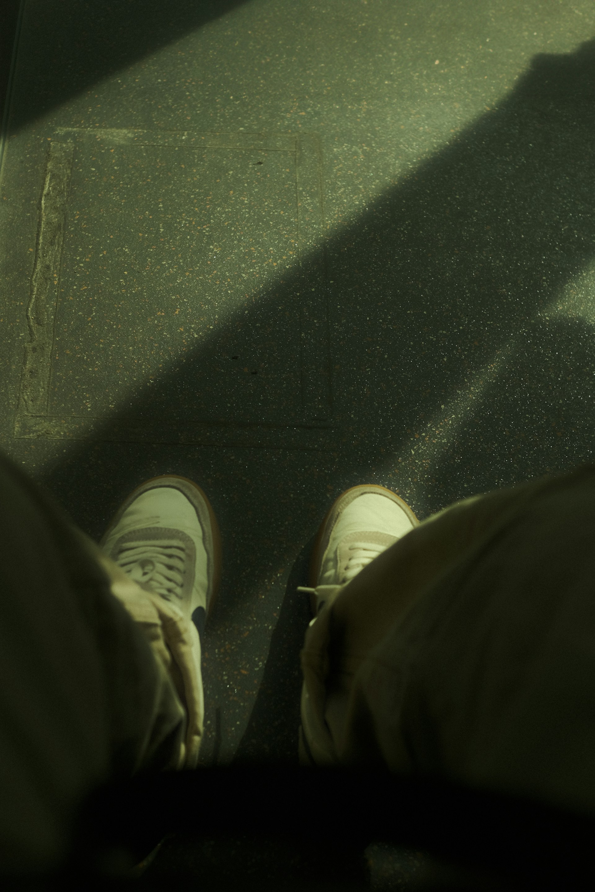 A person standing on a sidewalk with their feet up