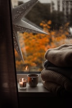 A window sill with candles and blankets on it