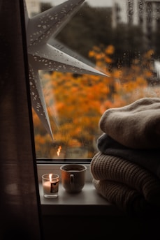 A window sill with candles and blankets on it