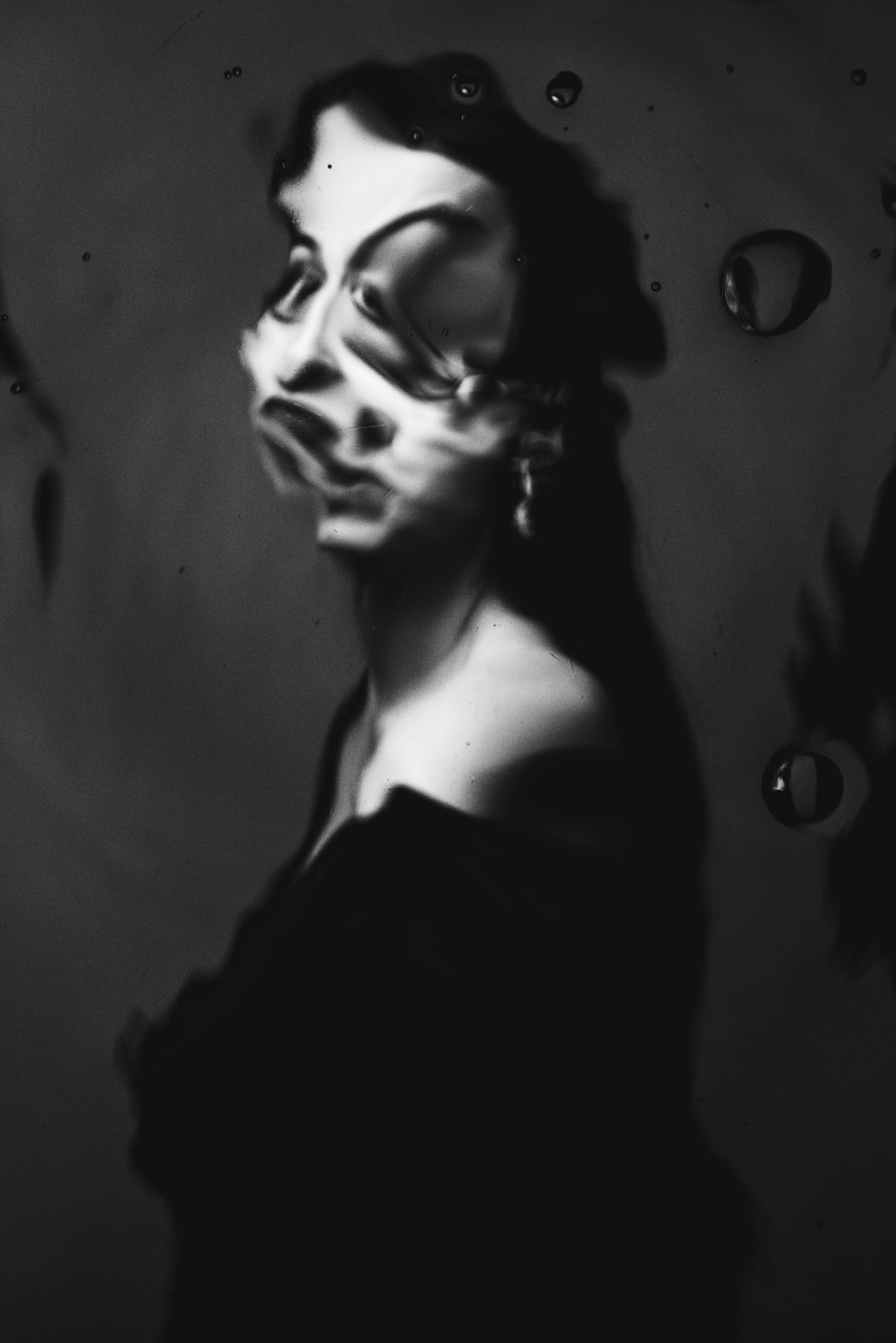 Une femme en robe noire debout devant des gouttelettes d’eau