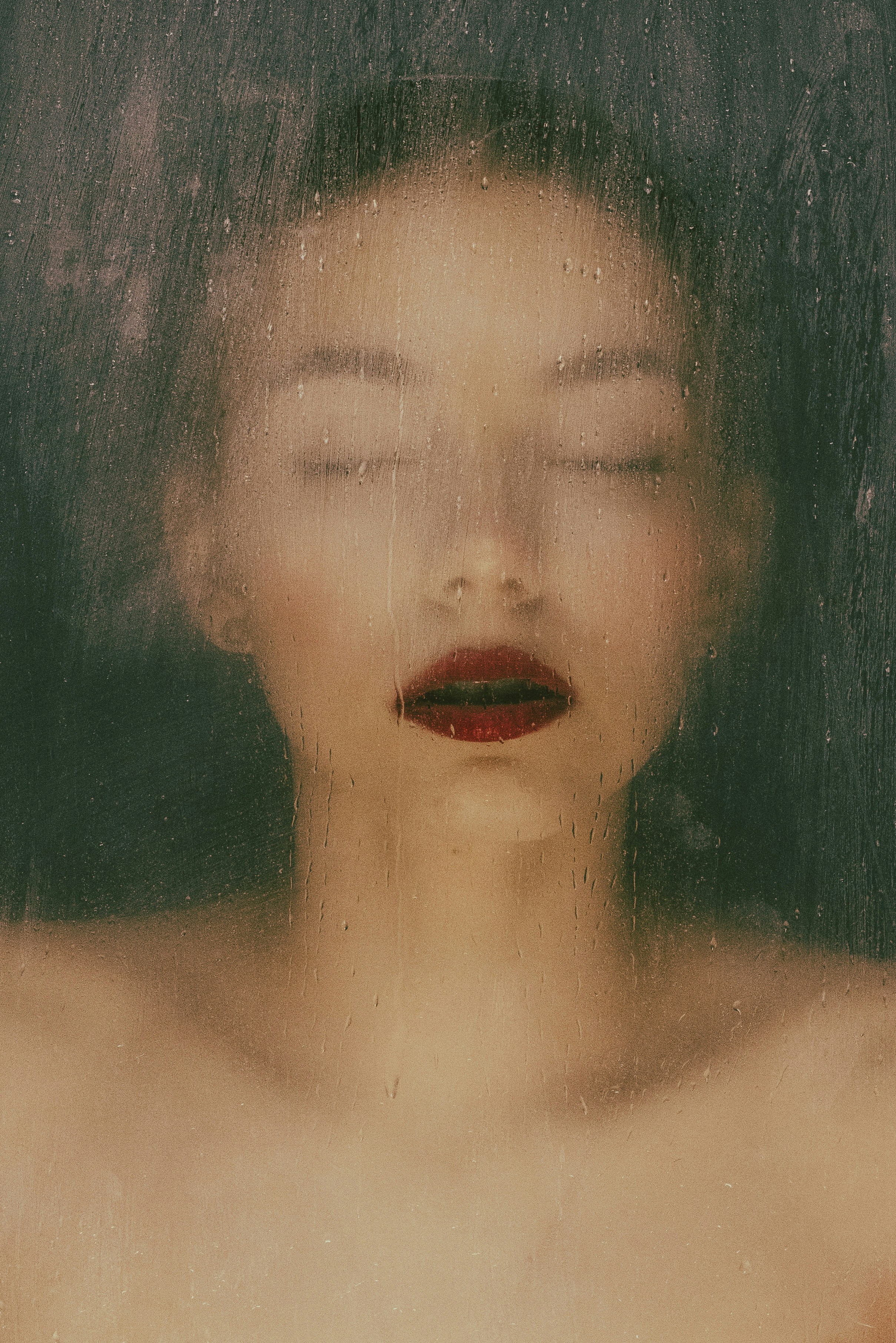 Une femme les yeux fermés debout devant une fenêtre