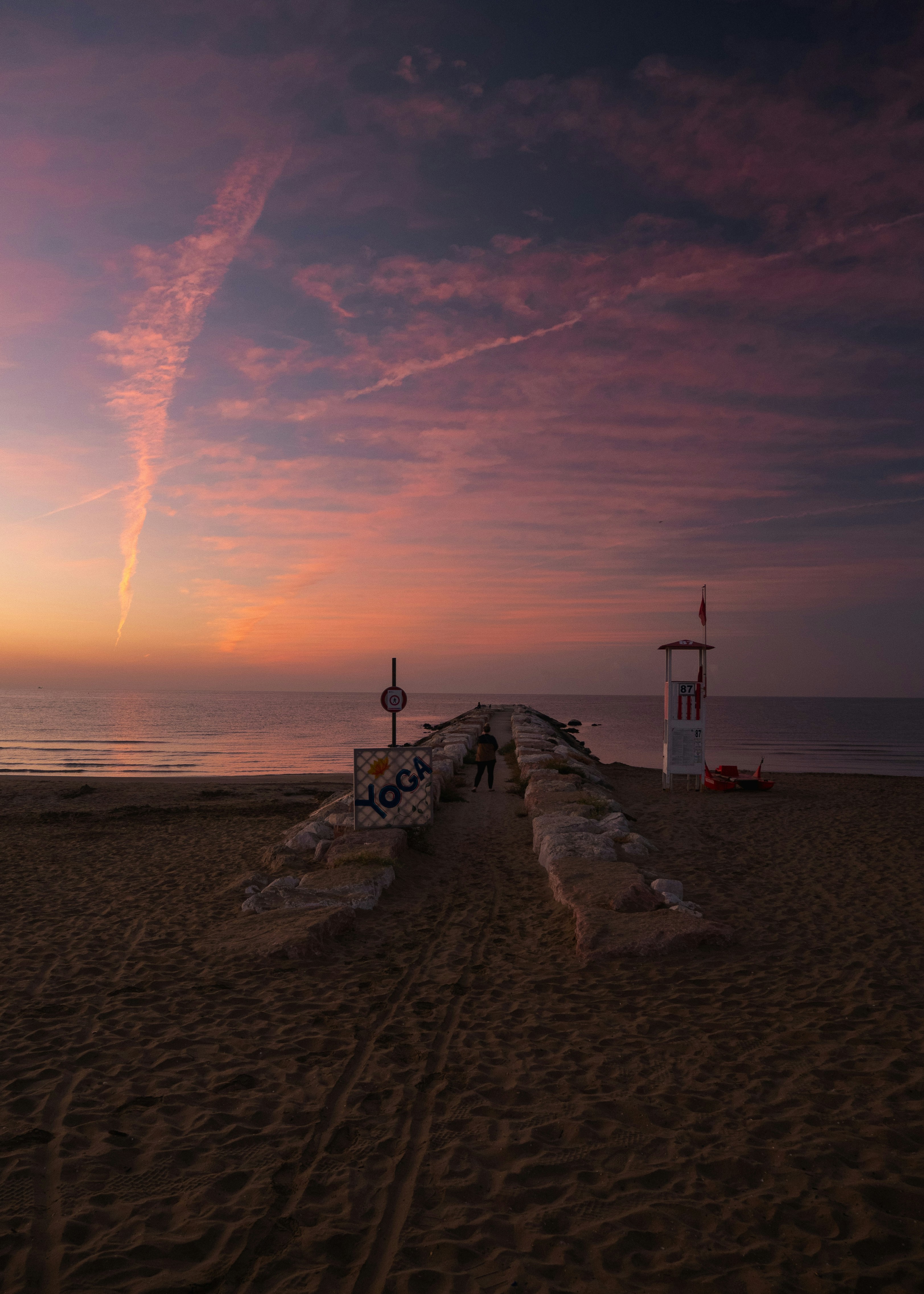 A long wooden bench sitting on top of a sandy beach