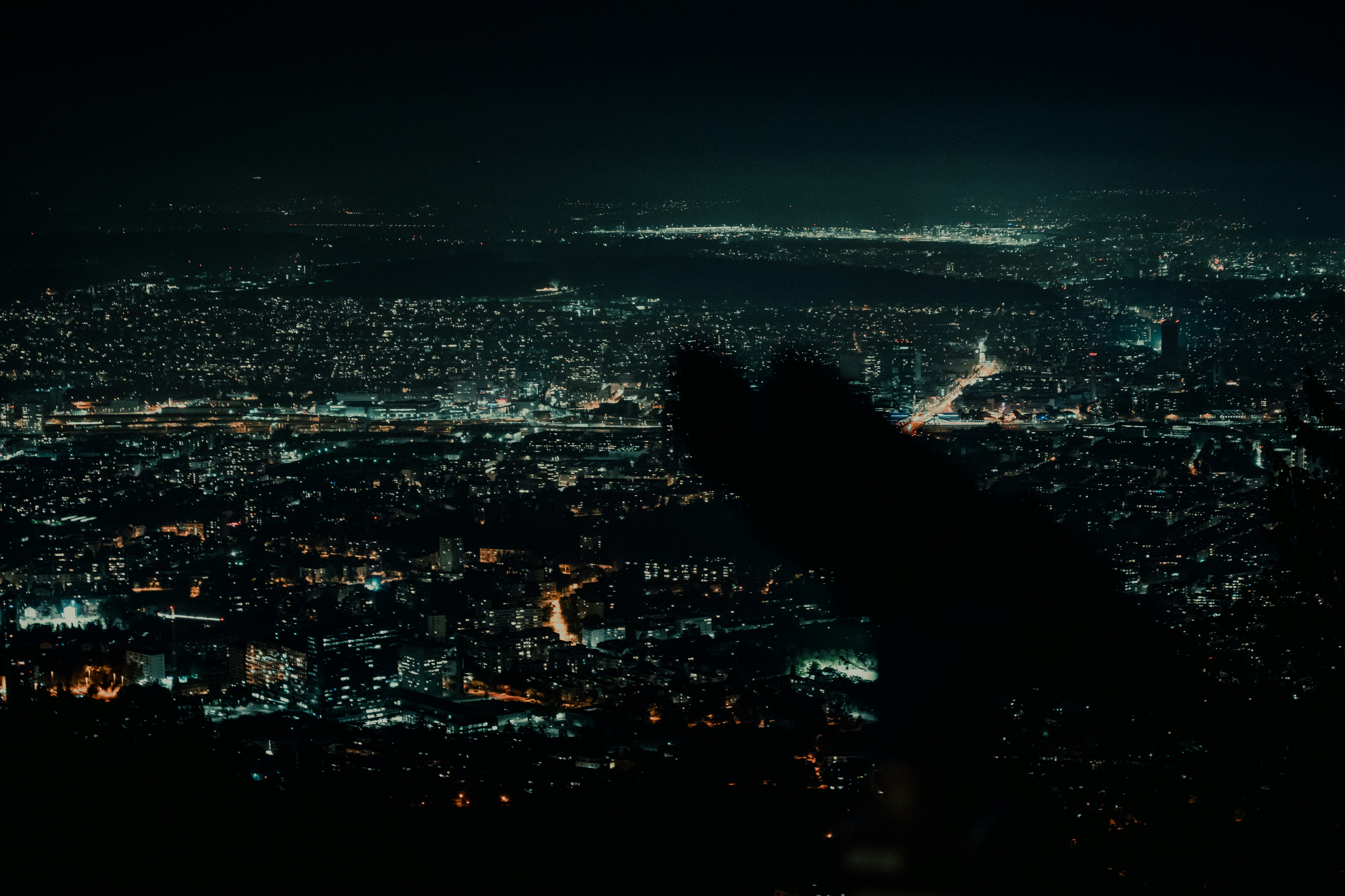 A view of a city at night from the top of a hill