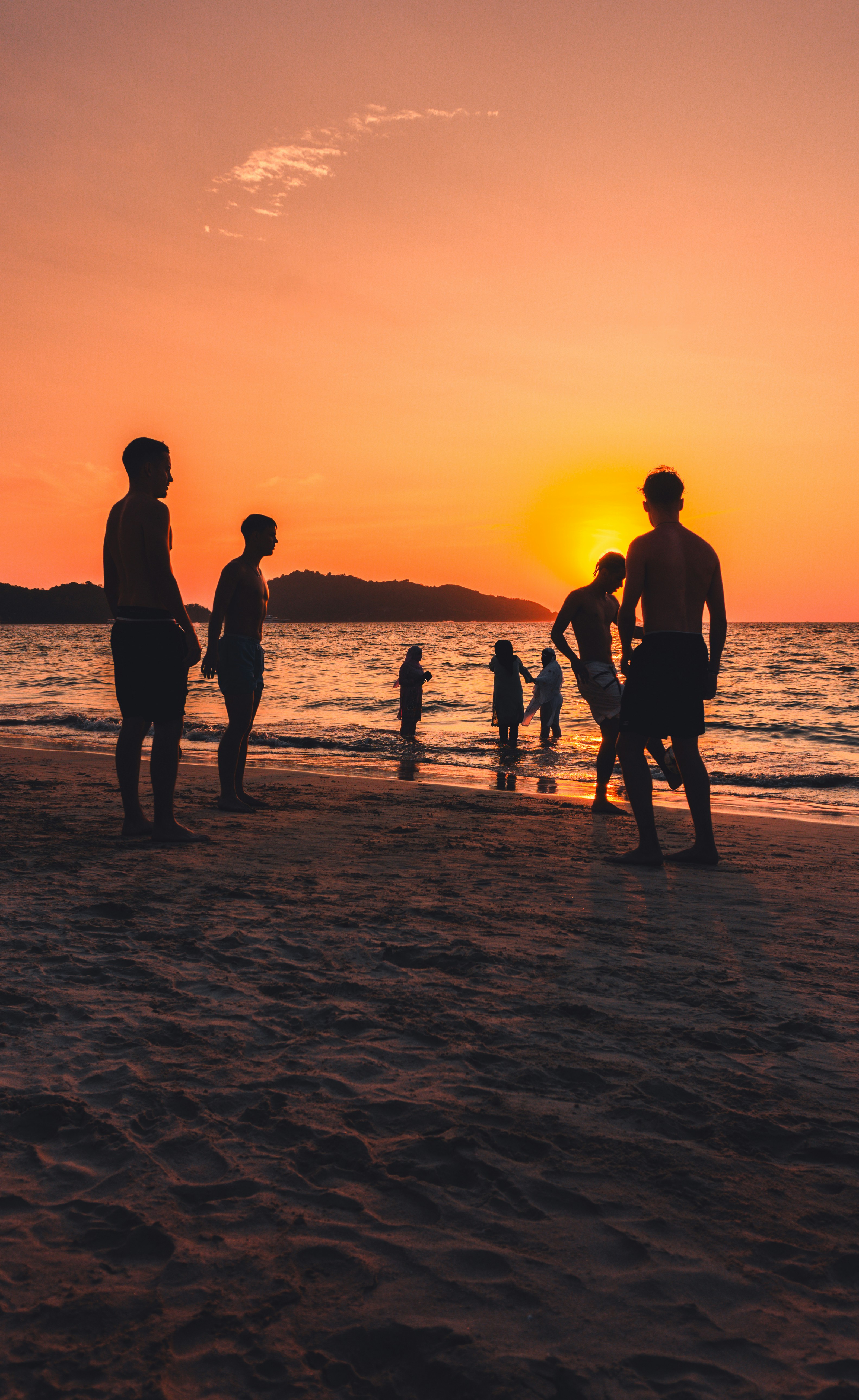 A group of people standing on top of a sandy beach