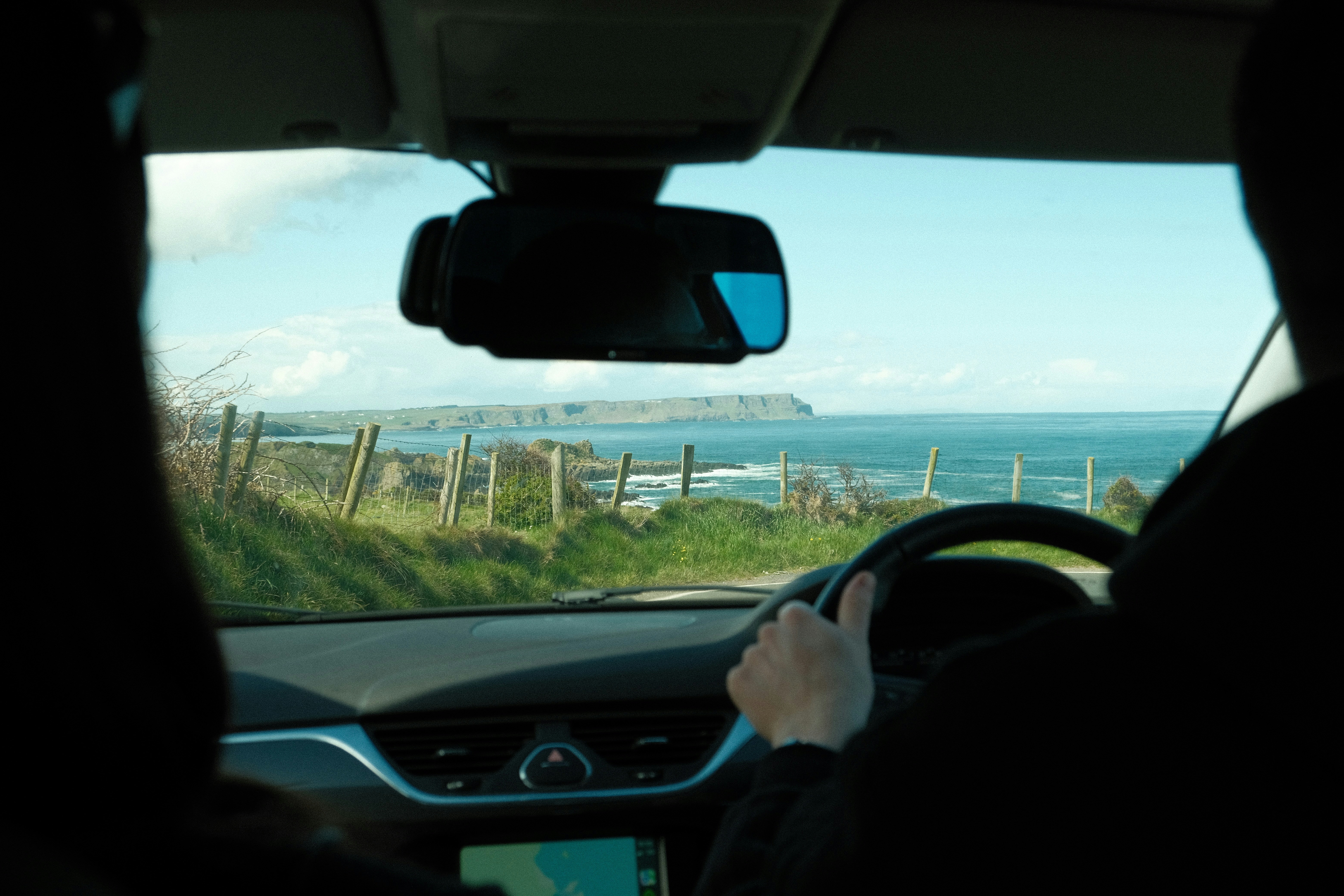 A man driving a car down a road next to the ocean