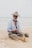 A man sitting on a beach next to a net