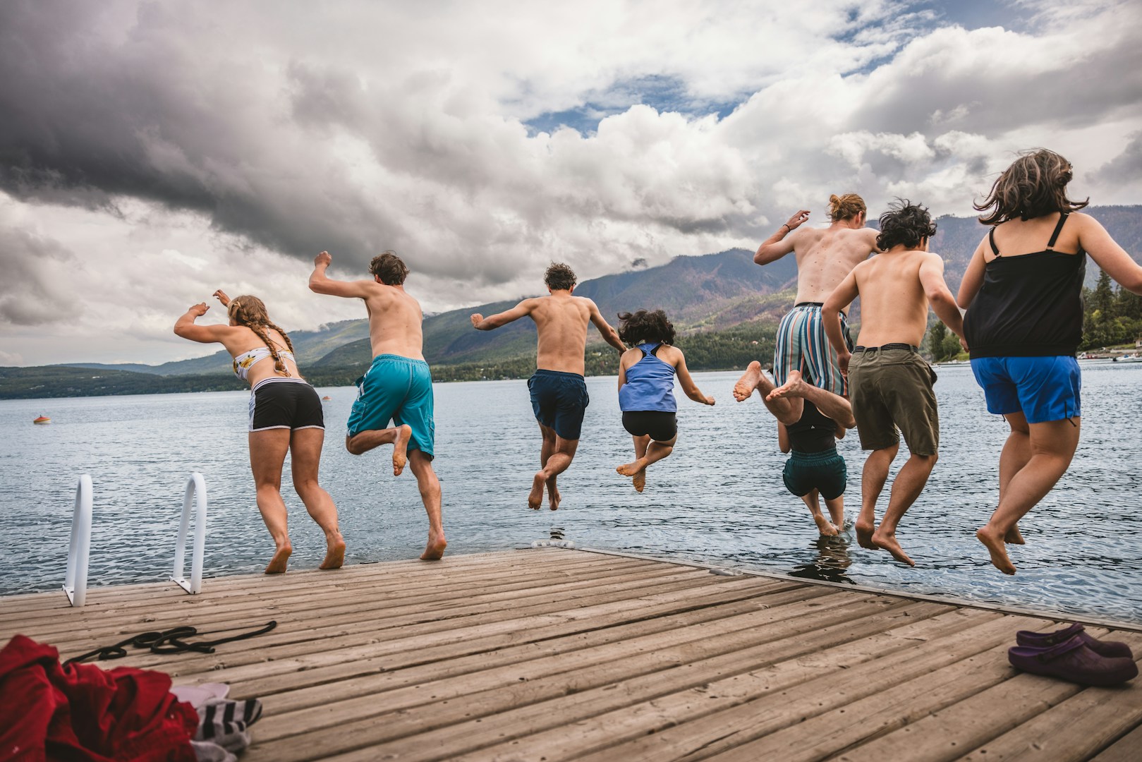 Friends jumping off a cottage dock into the lake