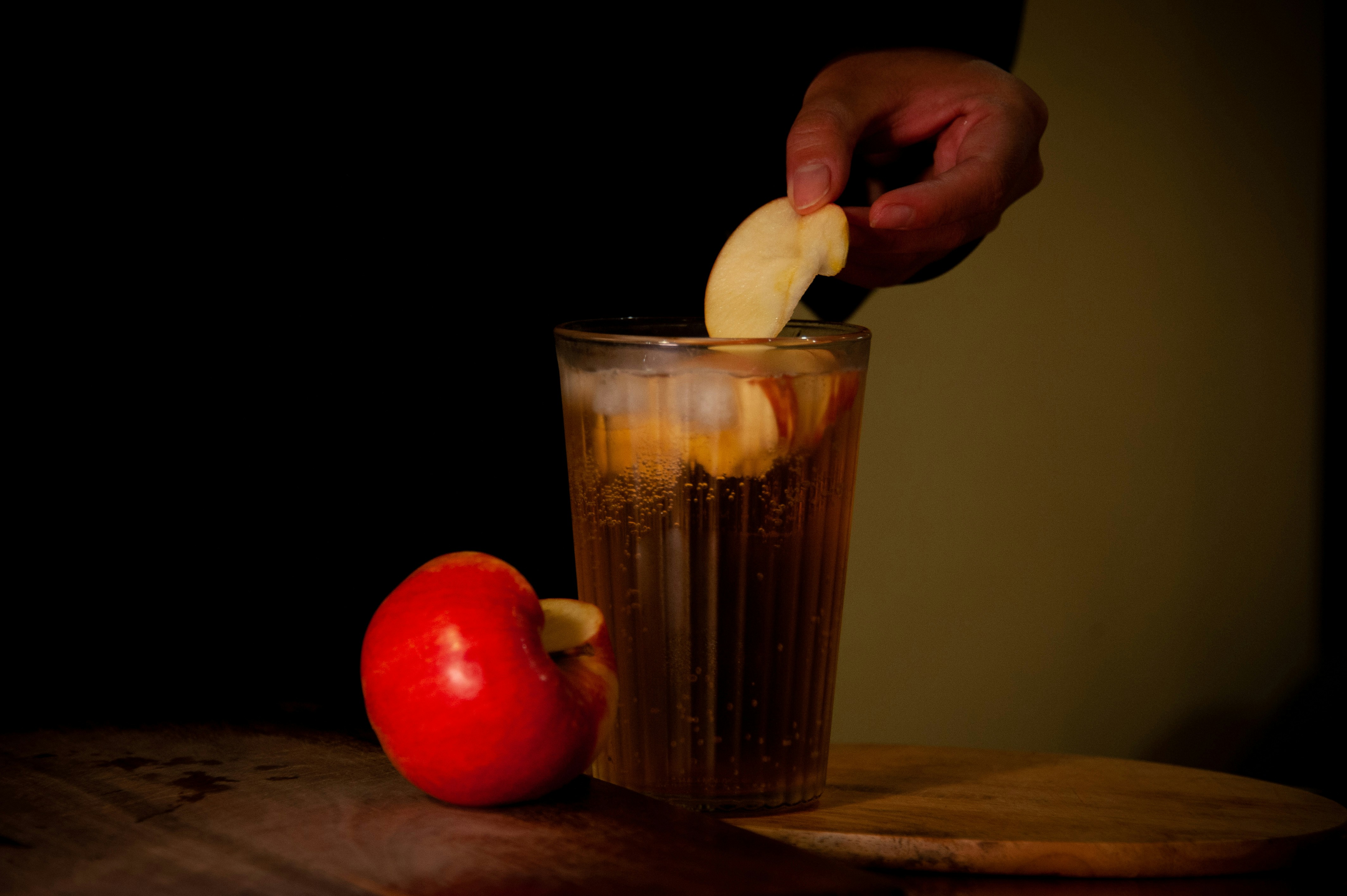 A person is putting an apple in a glass