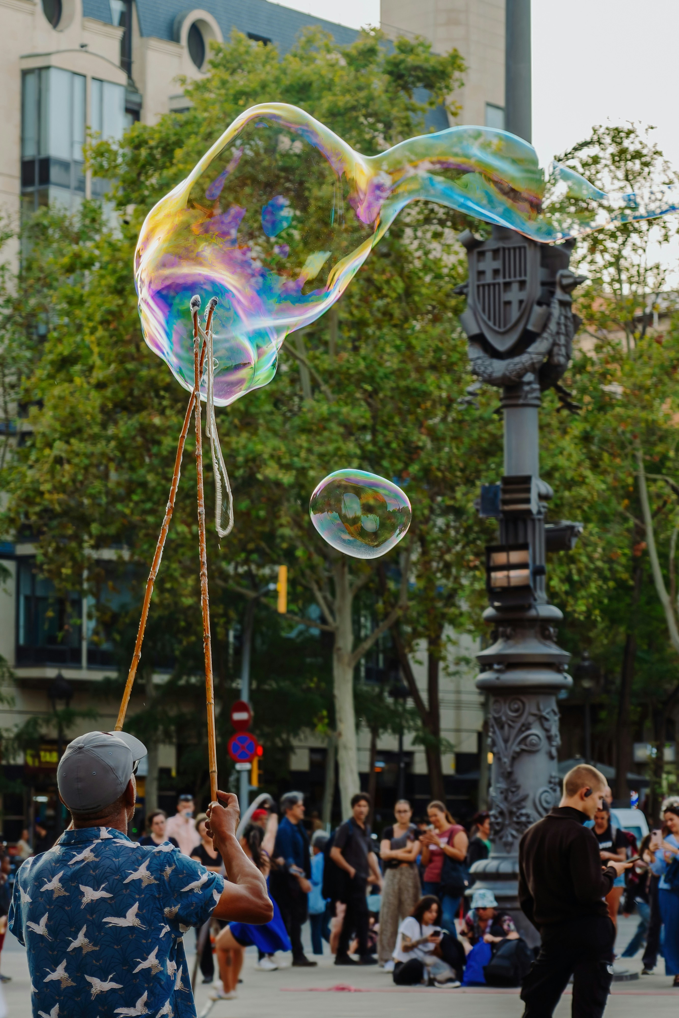 A man is blowing bubbles on a street light pole