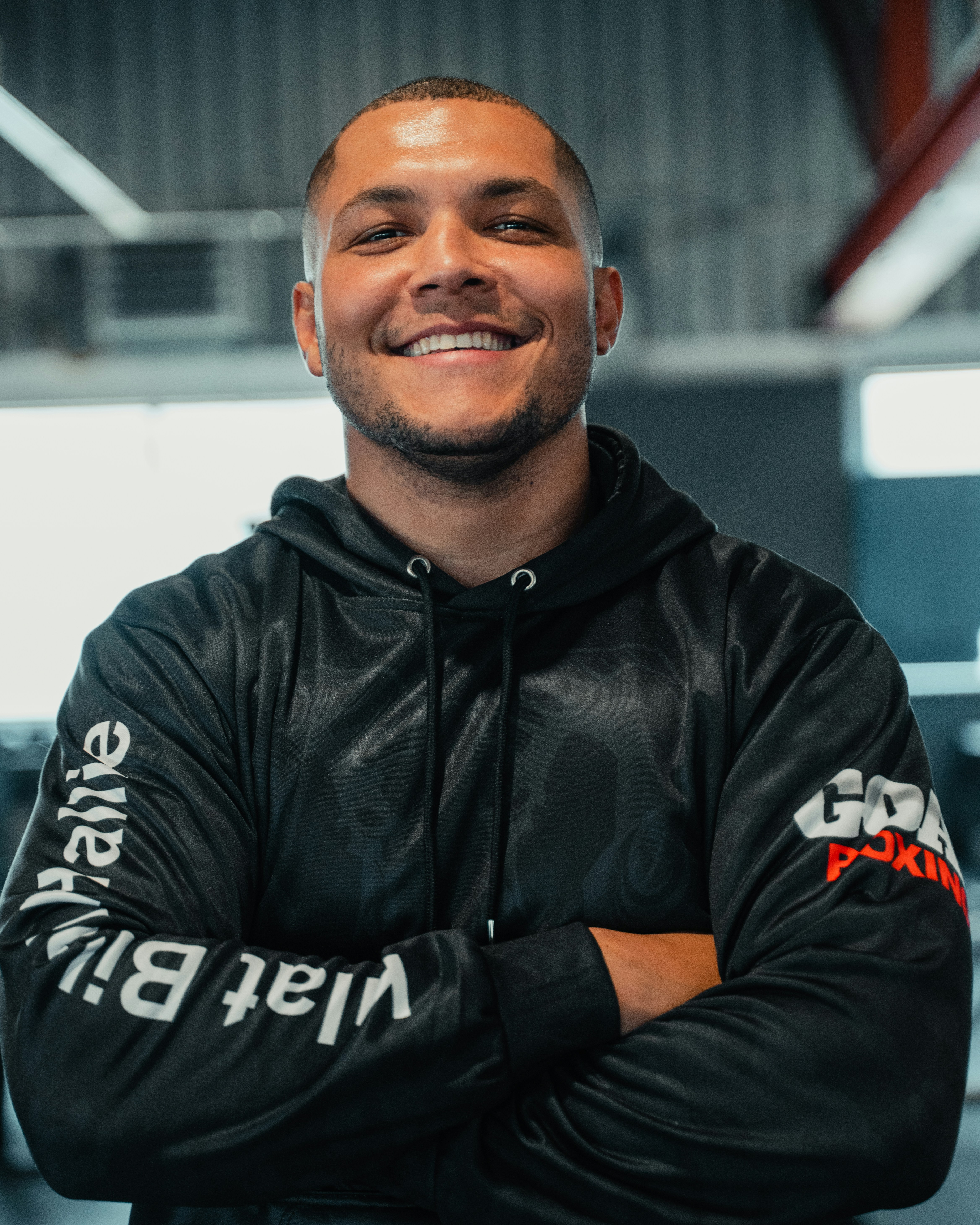 A smiling man in a black jacket with his arms crossed