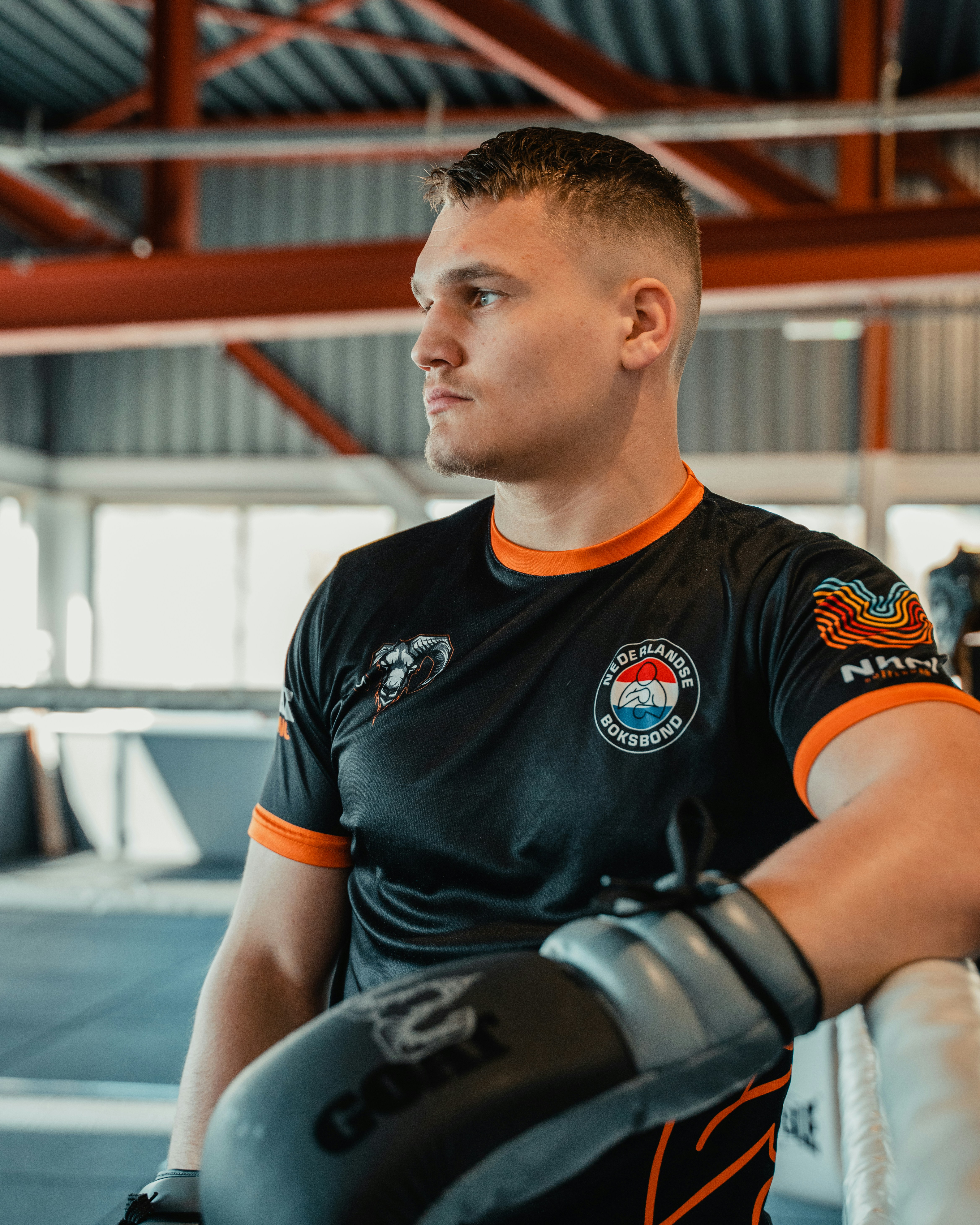 A man wearing a black and orange shirt and boxing gloves