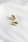 A pair of gold earrings sitting on top of a white sheet