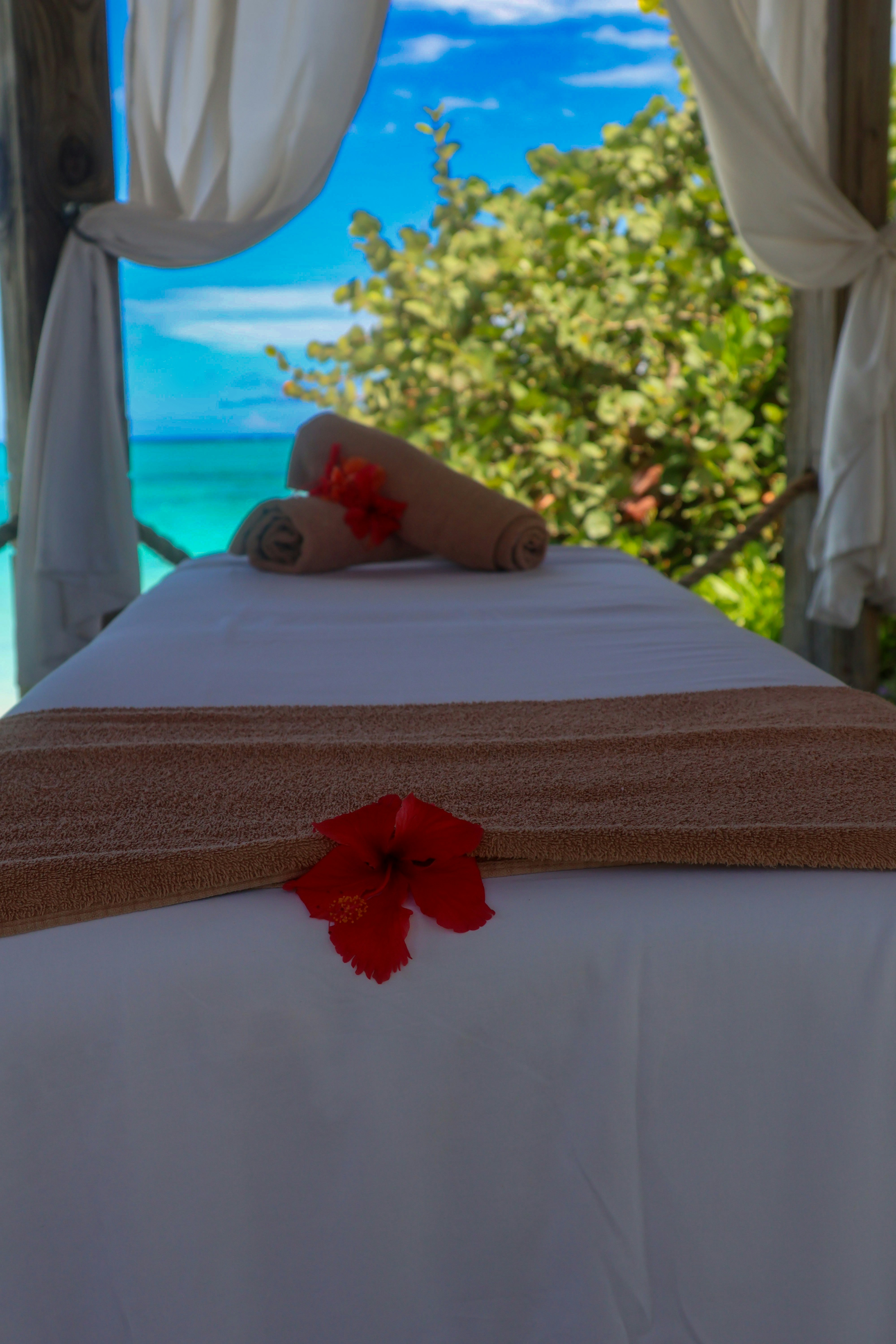 Person deeply relaxed during massage session, peaceful expression, warm soft lighting, ocean view through window